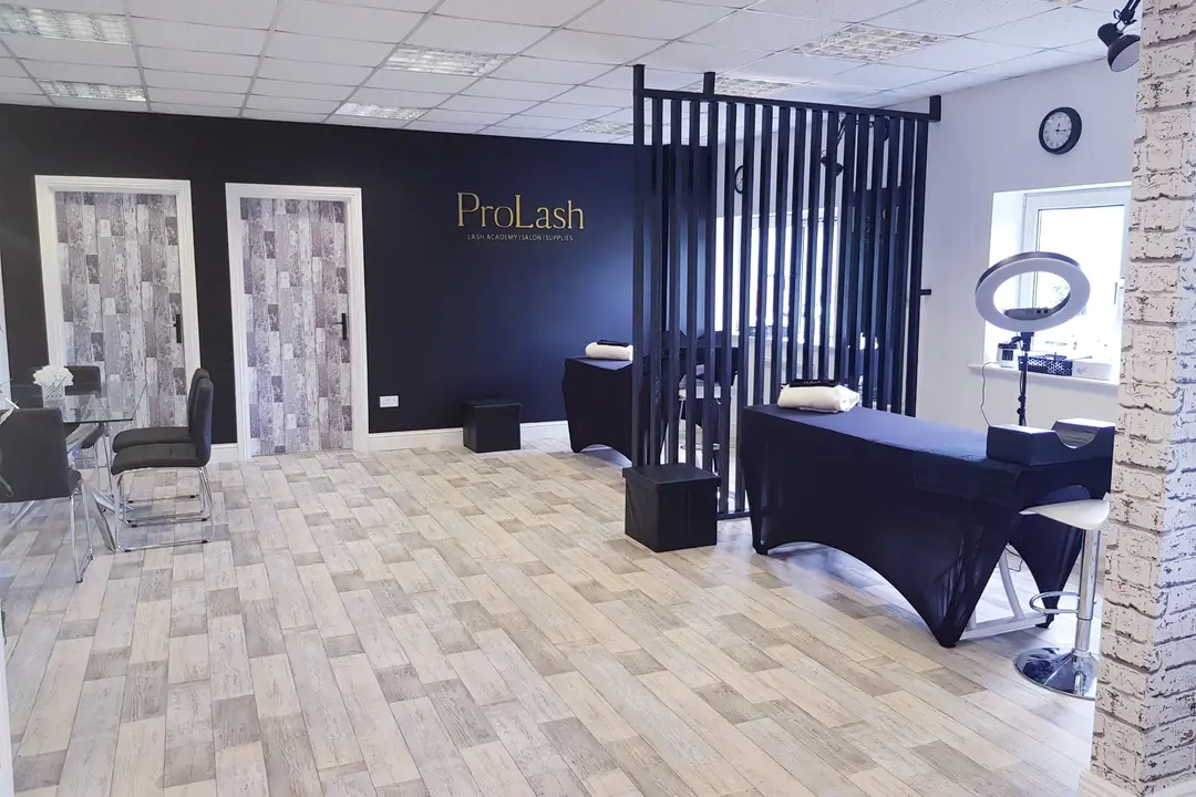 Training room of the first ProLash academy with the gold ProLash logo on a dark wall and two lash beds